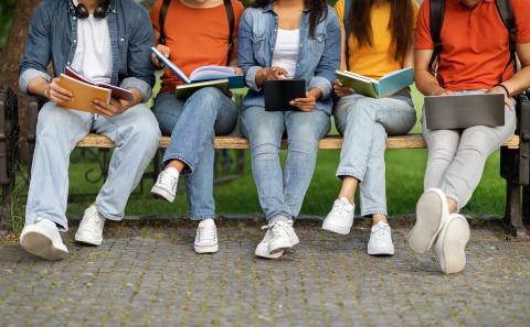 Jeans clad legs of college students sitting on a bench