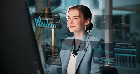 A young woman smiles as she sits at a computer